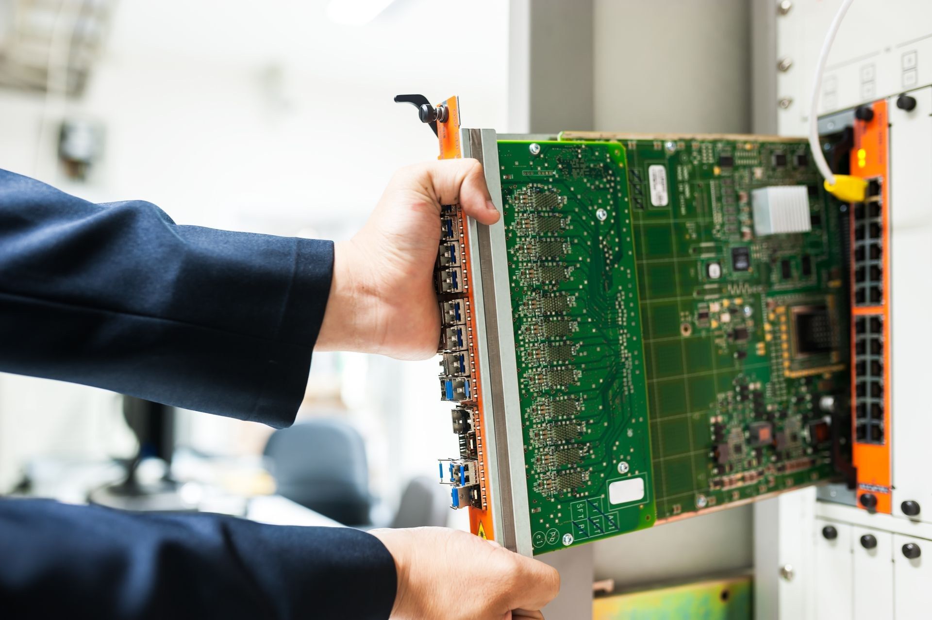 An engineer's hands sliding a line card into a chassis in a rack