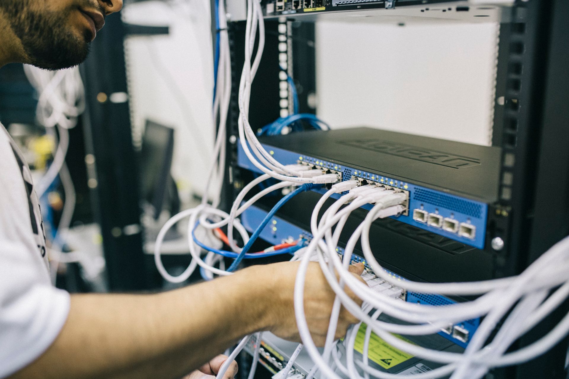 A technician patching network cables into a switch in a rack